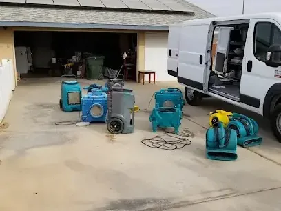 Air movers and dehumidifiers lined up on a driveway, ready for a dry-out