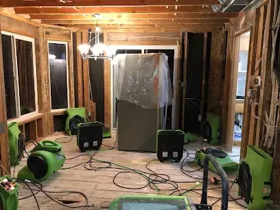 Green air movers drying a room gutted down to the framing