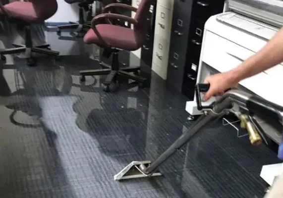 An extraction wand removing water from carpet tile in an office